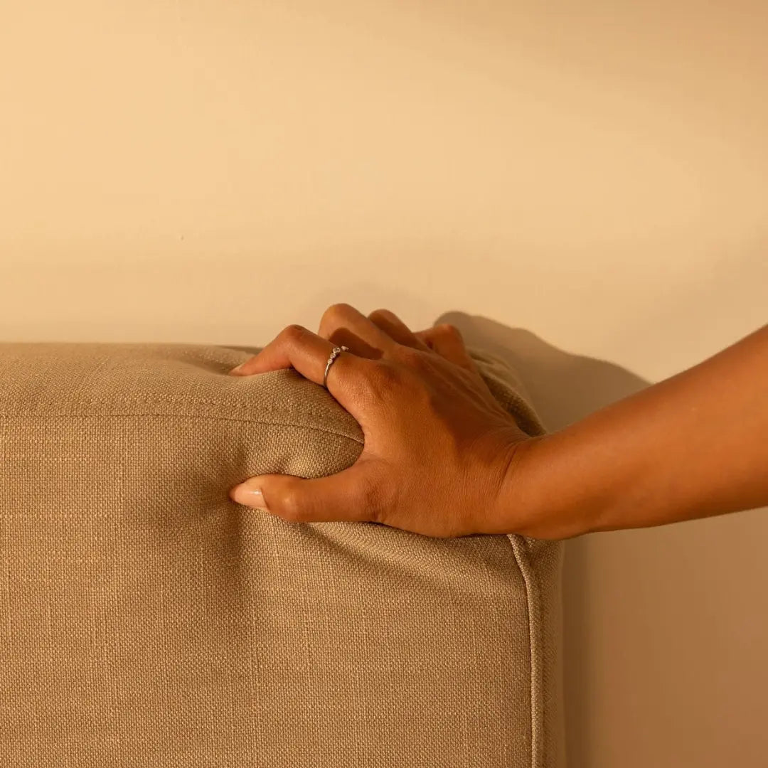 Hand touching a tan soft headboard with a neutral background | Ultra Headboard, Queen, Sahara | SoftFrame Designs