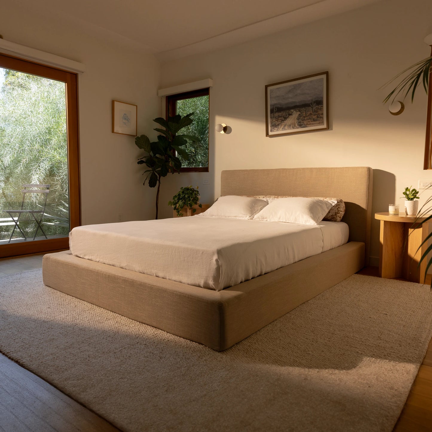 tan bed frame in a bedroom with large windows and plants | Ultra Set, Queen, Sahara| SoftFrame Designs