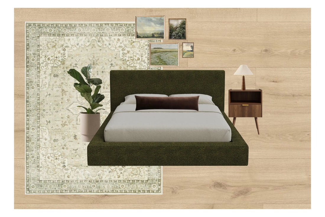 Warm and earthy styled bedroom with a dark upholstered SoftFrame Designs bed on a patterned rug, a bedside table with lamp, a potted plant, and framed wall art against light wood flooring.