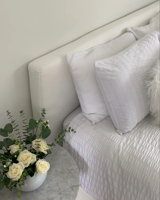 A Classic headboard from SoftFrame Designs with a bouquet of white flowers beside it