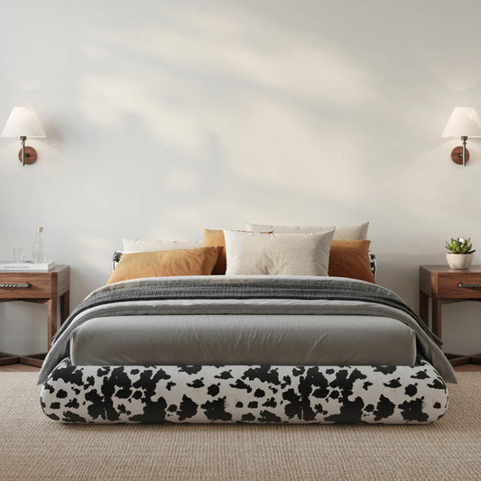 Bedroom with a all cushioned bed featuring a cow print fabric.
