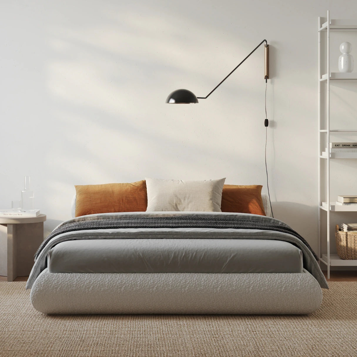 Modern bedroom with a all cushioned bed, lamp, and shelves.