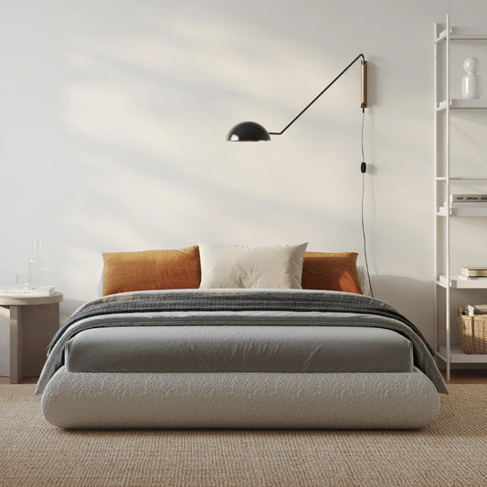 Modern bedroom with a all cushioned bed, lamp, and shelves.