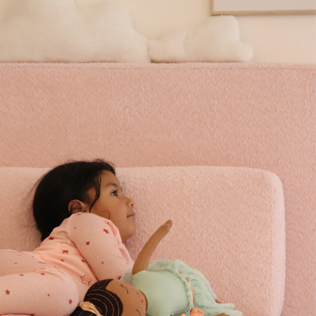 Child resting their head on a pink wedge pillow against a cushioned headboard | SoftFrame Designs
