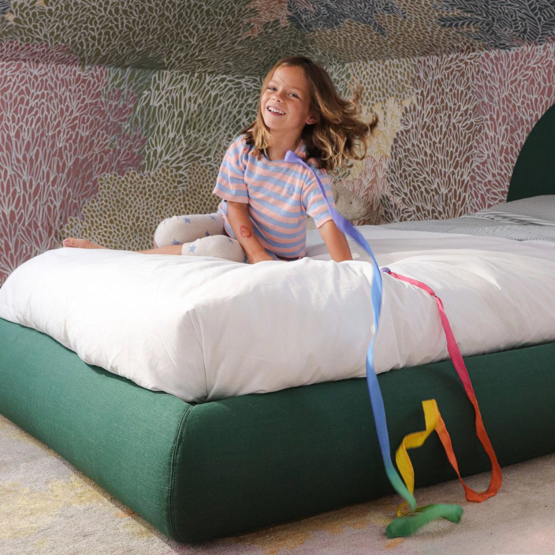 Girl playing on a all cushioned green bed frame