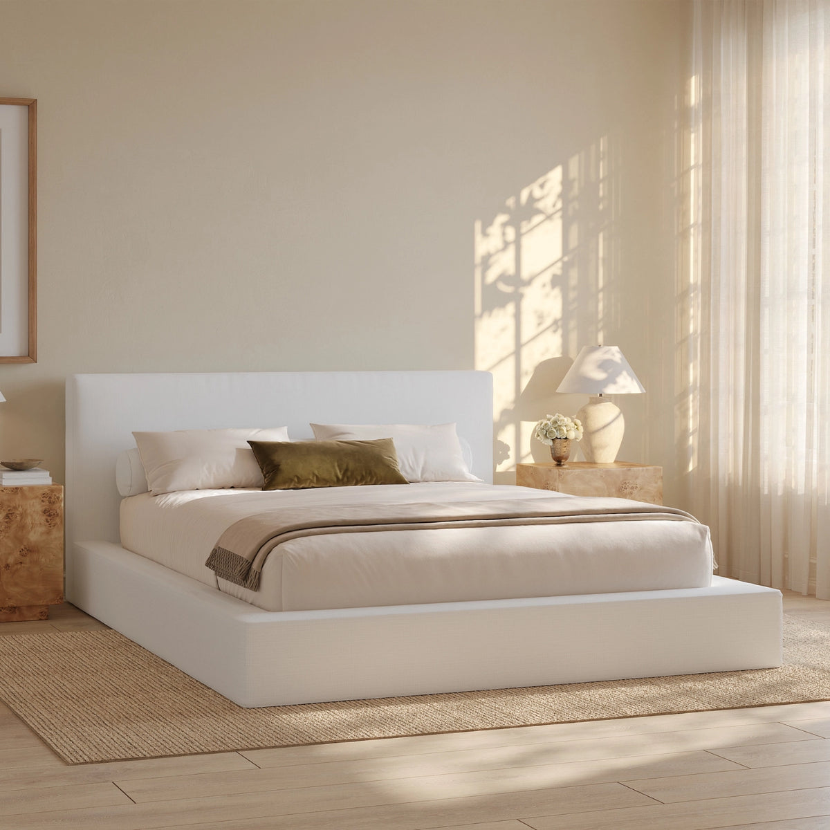 Modern bedroom with a all cushioned bed and neatly made bed in a bright room with large windows.