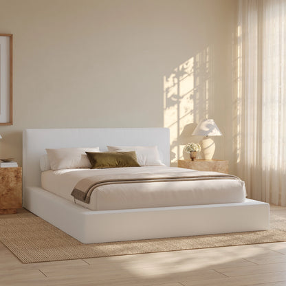 Modern bedroom with a all cushioned bed and neatly made bed in a bright room with large windows.
