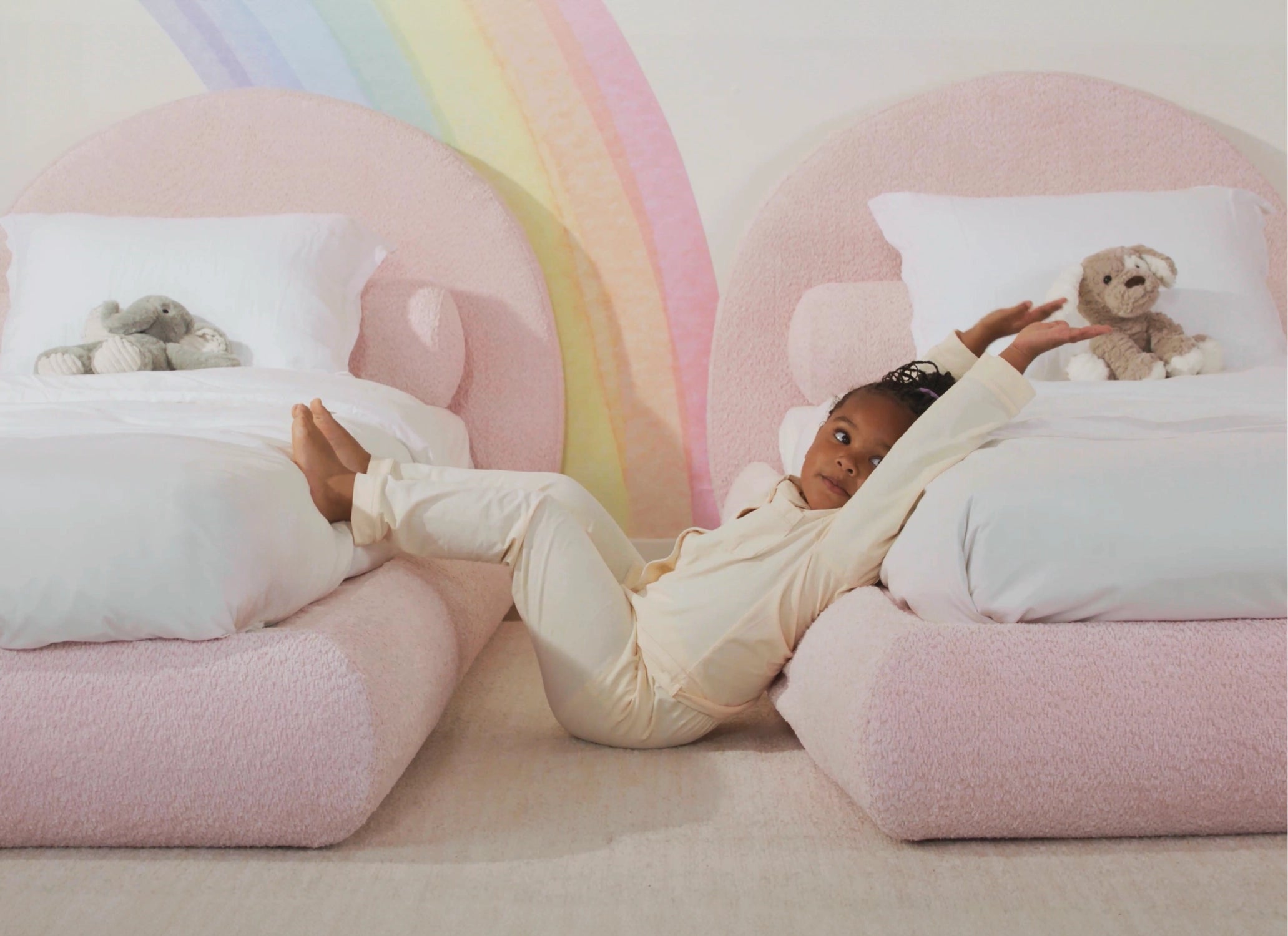 Child reading a book on a pink all cushioned bed with a patterned headboard