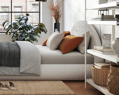 Modern living room with a all cushioned headboard, decorative pillows, and a white shelf.