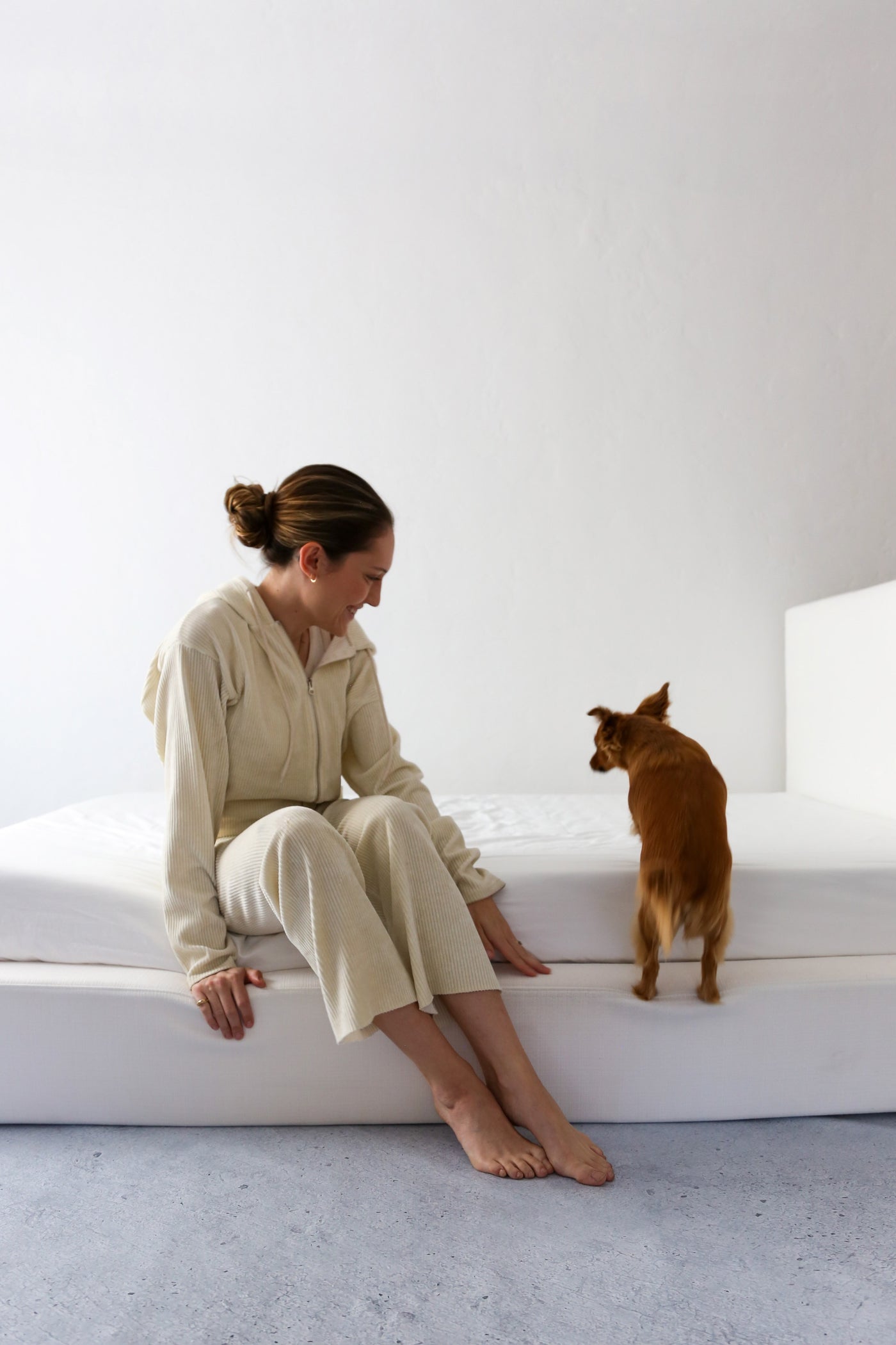 Woman and Dog Sitting on a White Upholstered SoftFrame Bed Frame
