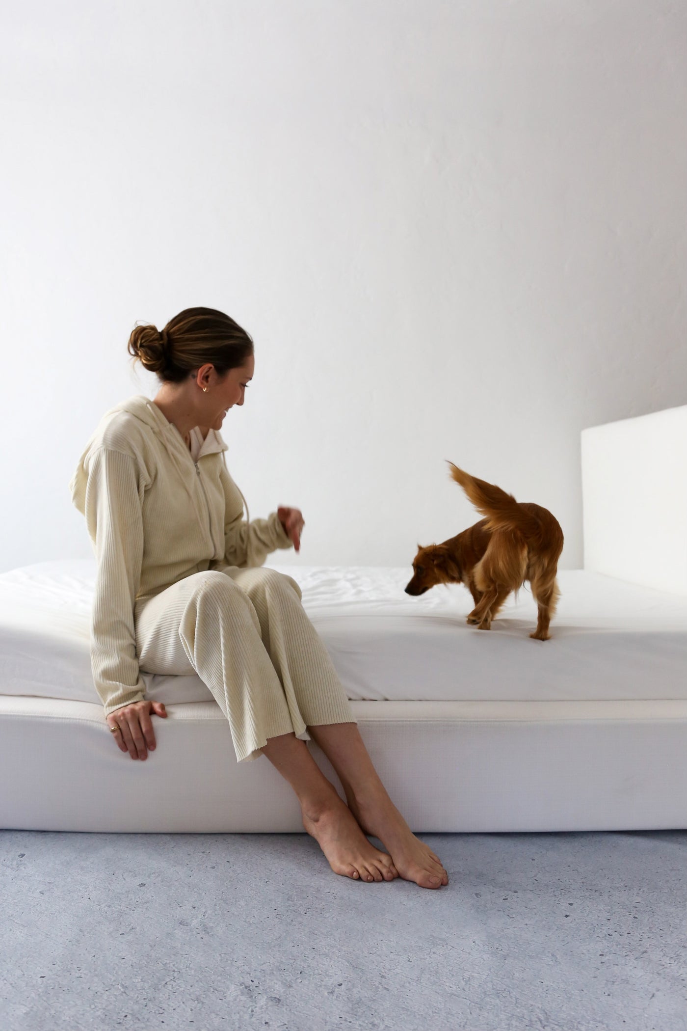 Woman and Dog on a White Upholstered Bed Frame