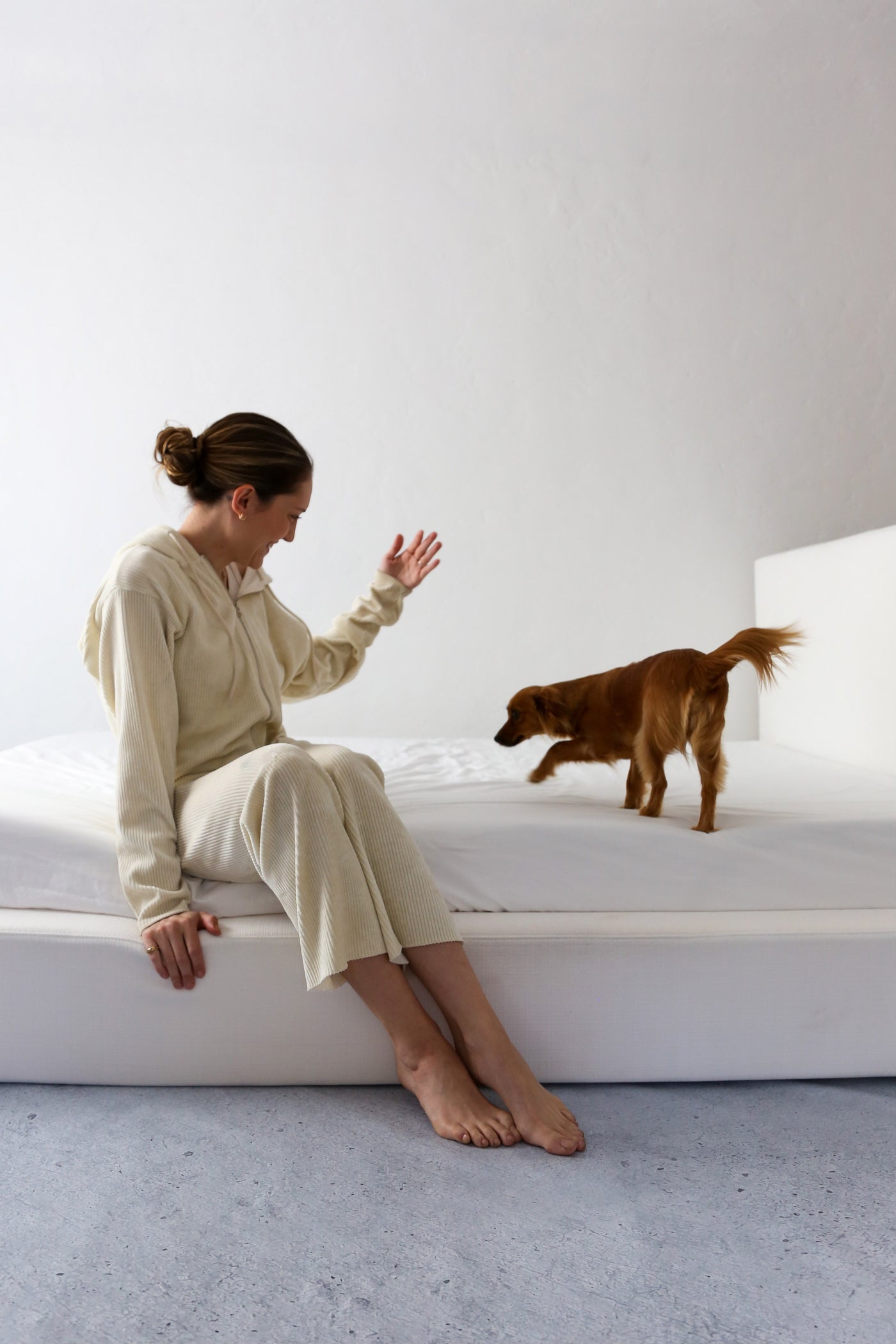 Woman Playing With Dog on a White Upholstered Bed Frame