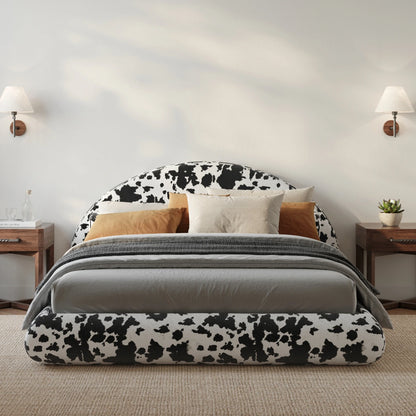 All cushioned bed with cow print headboard and gray bedding in a bedroom setting.