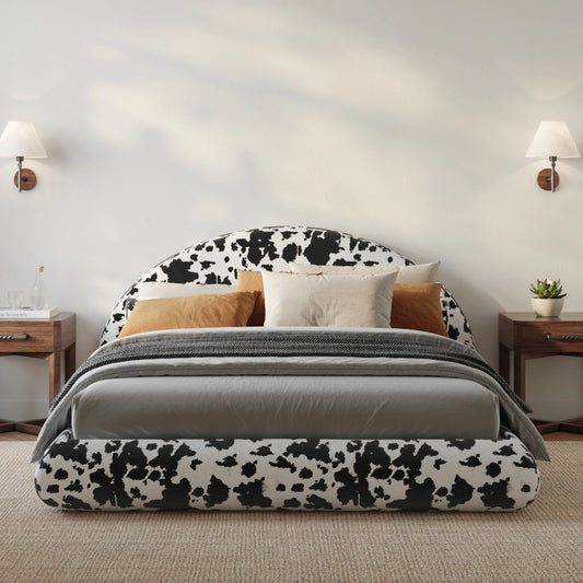 All cushioned bed with cow print headboard and gray bedding in a bedroom setting.