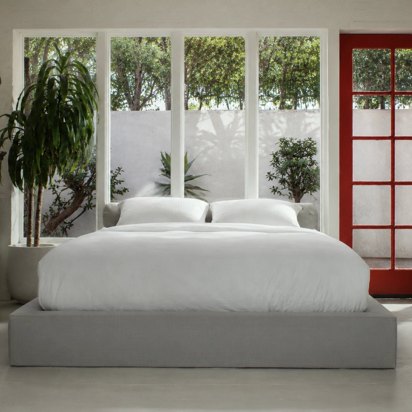 Gray cushioned bed frame with a window view