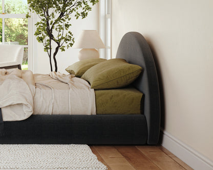 Bedroom with a bed featuring green pillows and a lamp in the corner.