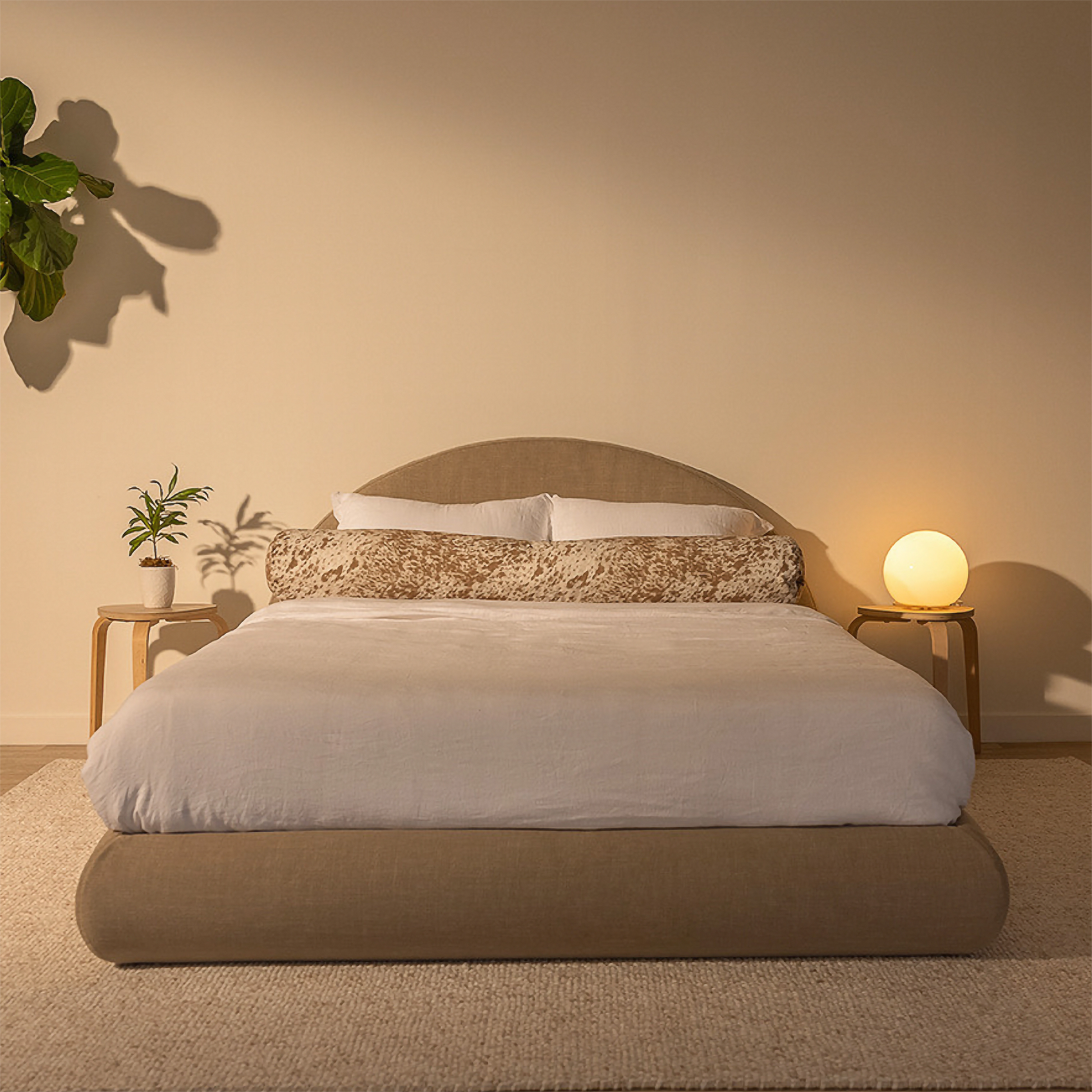 Bedroom with a tan soft bed frame, nightstands, and decorative items on a beige wall background | Luna Set, Queen, Sahara | SoftFrame Designs