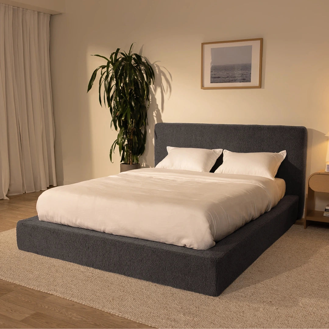 Bedroom with a dark grey, cloud bed frame, plant, and framed picture on the wall | Ultra Set in Storm | SoftFrame® Designs