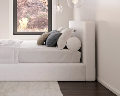 Modern bedroom with a all cushioned bed and decorative pillows near a window.