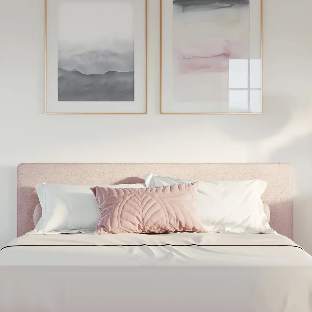 Bedroom with a pink all cushioned headboard and framed abstract art on the wall.