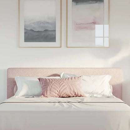 Bedroom with a pink all cushioned headboard and framed abstract art on the wall.
