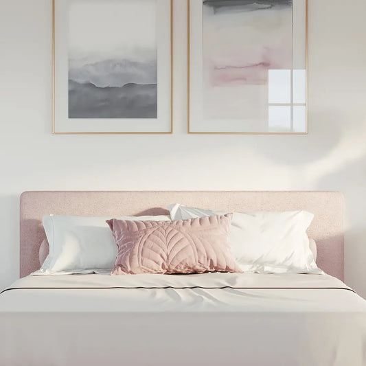 Bedroom with a pink all cushioned headboard and framed abstract art on the wall.