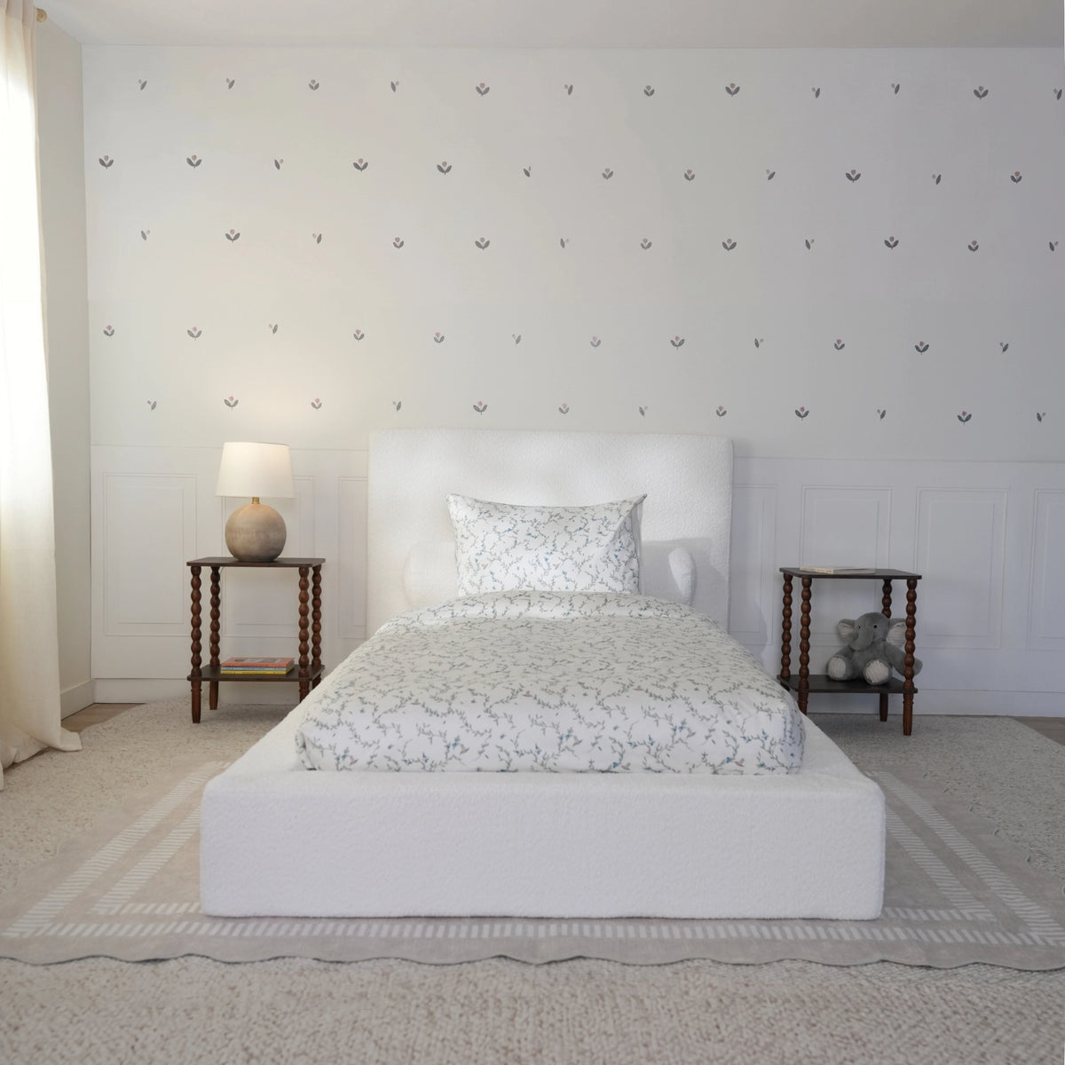 White kids all cushioned dbed frame with a soft texture. Decorated in a. neutral room with toys. front view