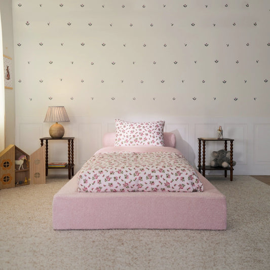 Cotton candy bed frame front view. All cushioned pink bed frame in a kids bed room with floral decal and toys.