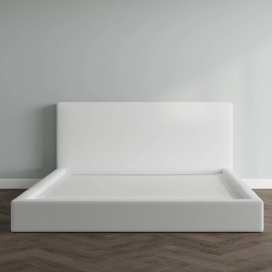 White bed frame against a gray wall on a wooden floor