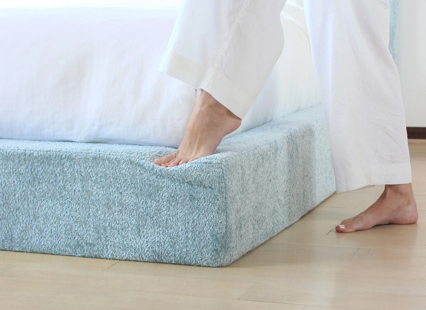 Person stepping onto a textured all cushioned bed frame.