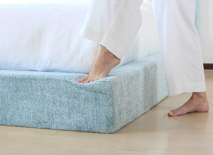 Person stepping onto a textured all cushioned bed frame.