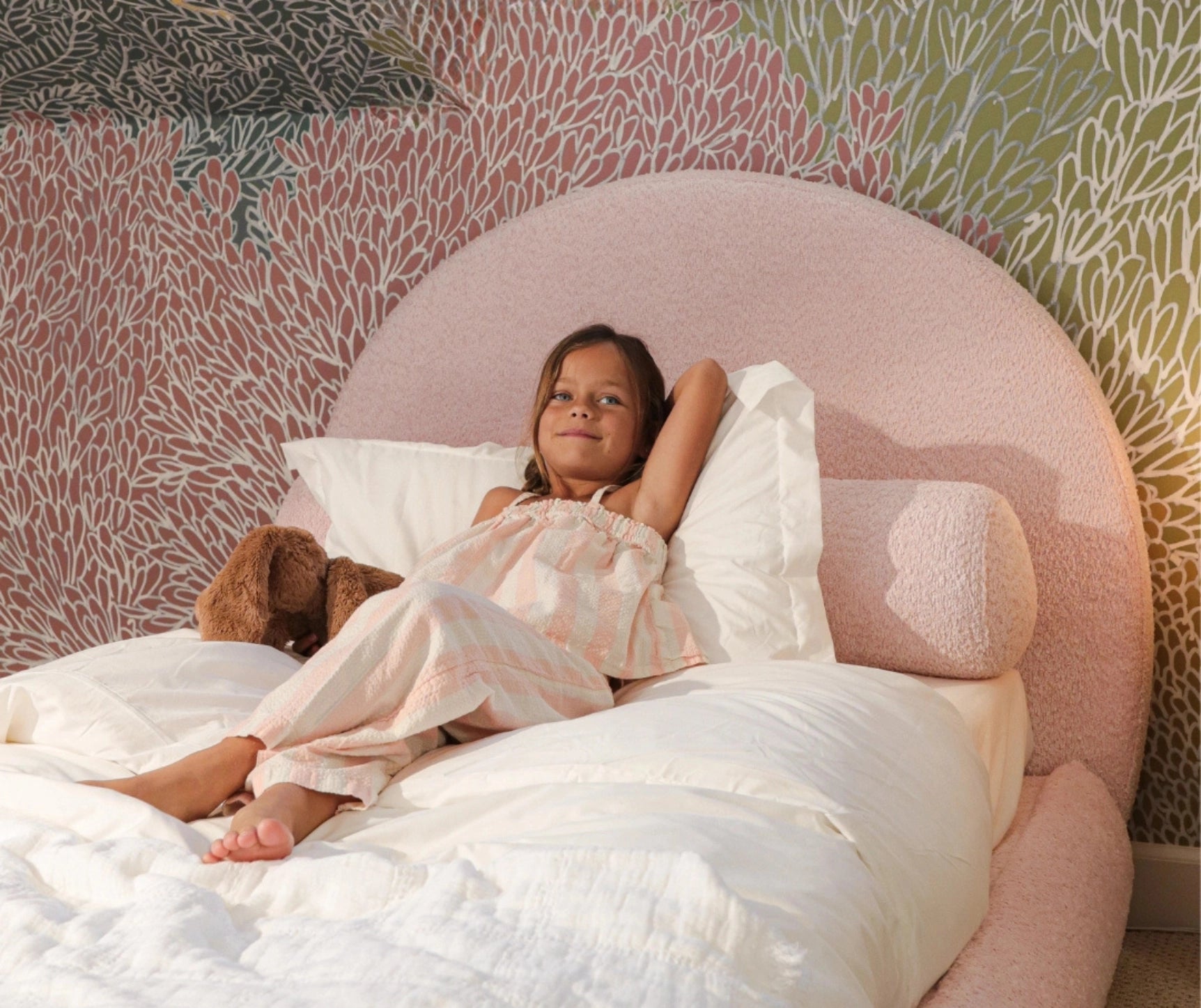 Girl in a pink bed with a round bolster pillow