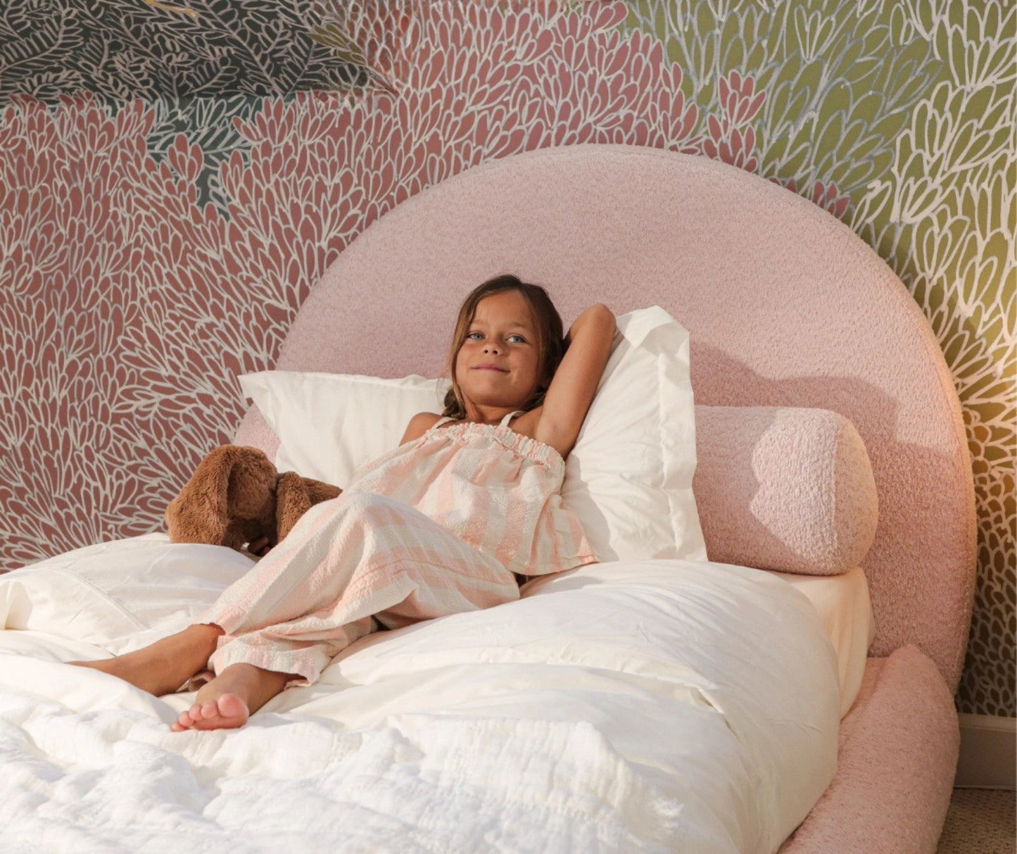 Girl in a pink bed with a round bolster pillow