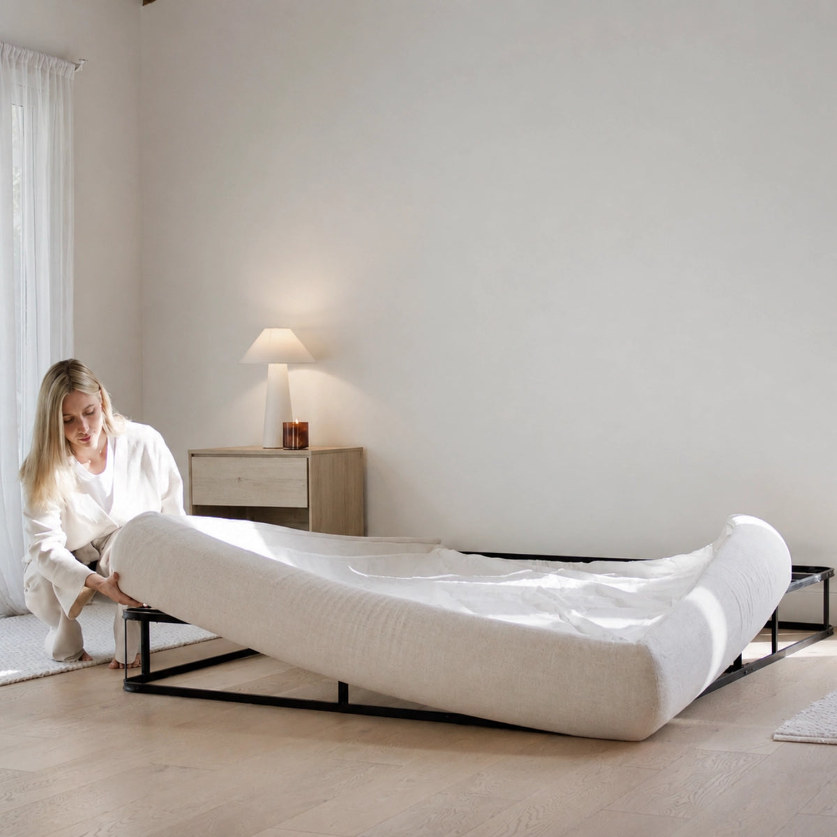 Woman setting up a round bed frame over a box spring in a modern, minimalistic room