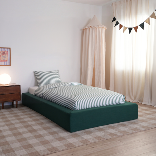 All cushioned bed frame in green forest by softframe designs with striped sheets and neutral decor for kids