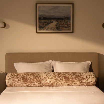 Bedroom with a bed featuring a round pillow, with a painting on the wall | Round Bolster Pillow, Queen, Pony | SoftFrame Designs
