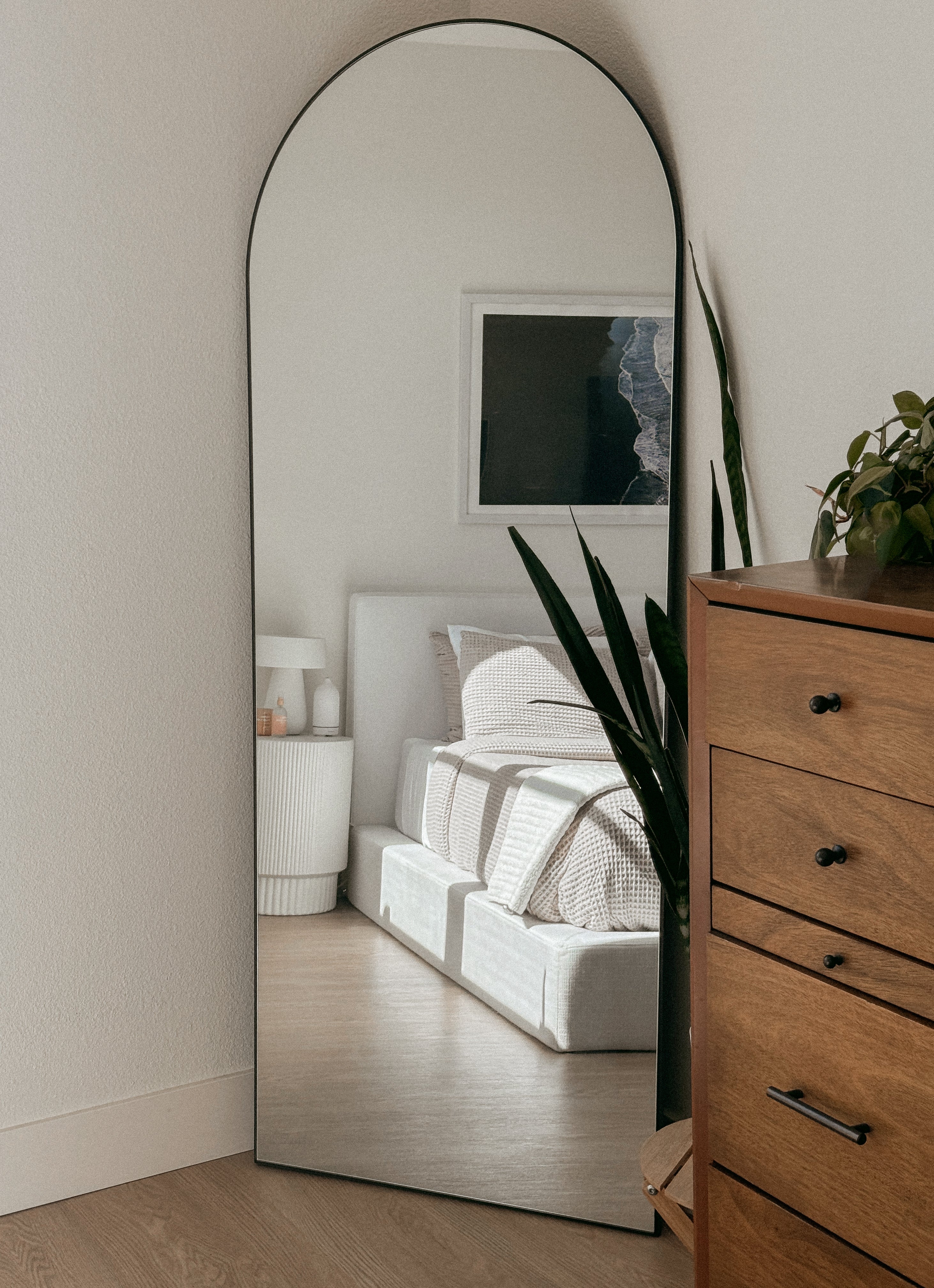 White soft bed set seen in the reflection of a mirror of a cozy bedroom setting