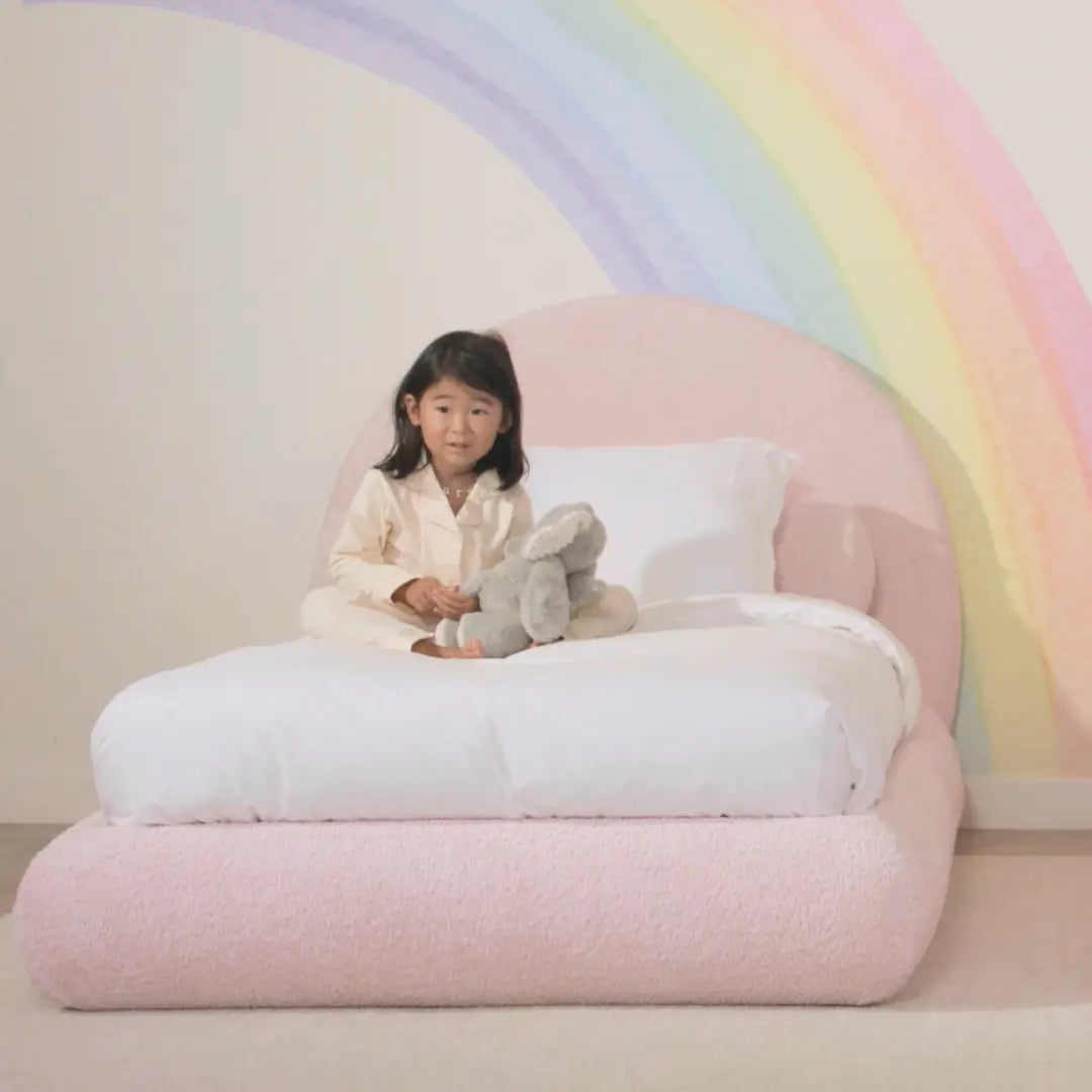 Child sitting on a large inflatable chair with a rainbow in the background