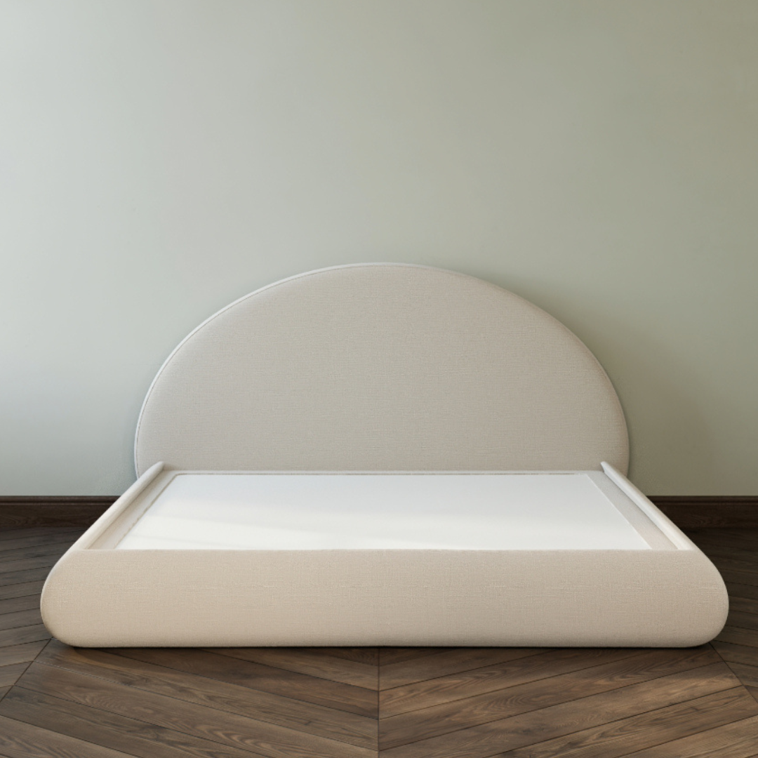 Beige upholstered headboard on a wooden floor with a plain wall background