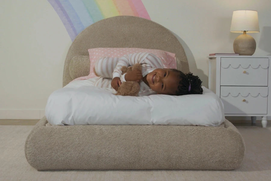 Child sleeping on a bed with a teddy bear, surrounded by a rainbow on the wall | SoftFrame Kids