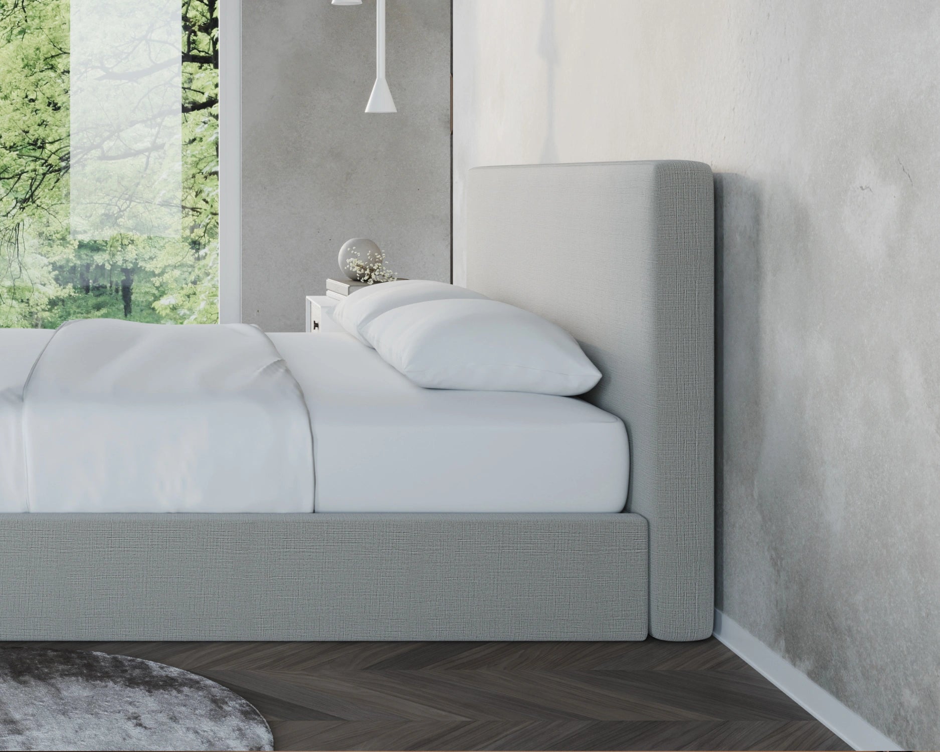 Gray upholstered all cushioned bed against a concrete wall with a window view