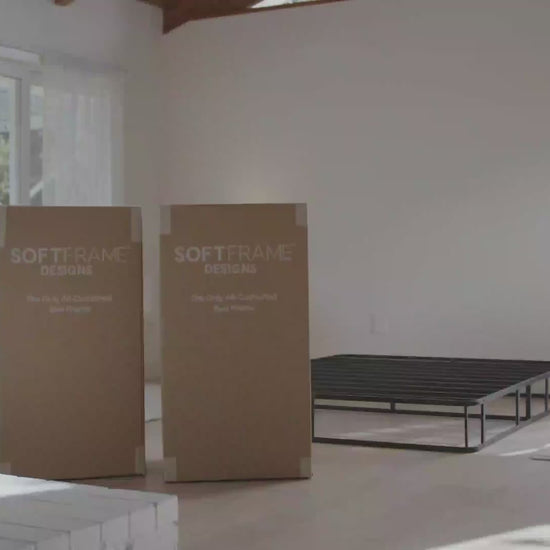 A woman setting up all cushioned ultra bed set from SoftFrame Designs in the Dune color in a airy minimalist room.