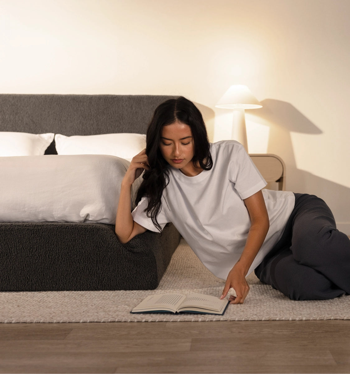 Woman reading a book on the floor in a bedroom