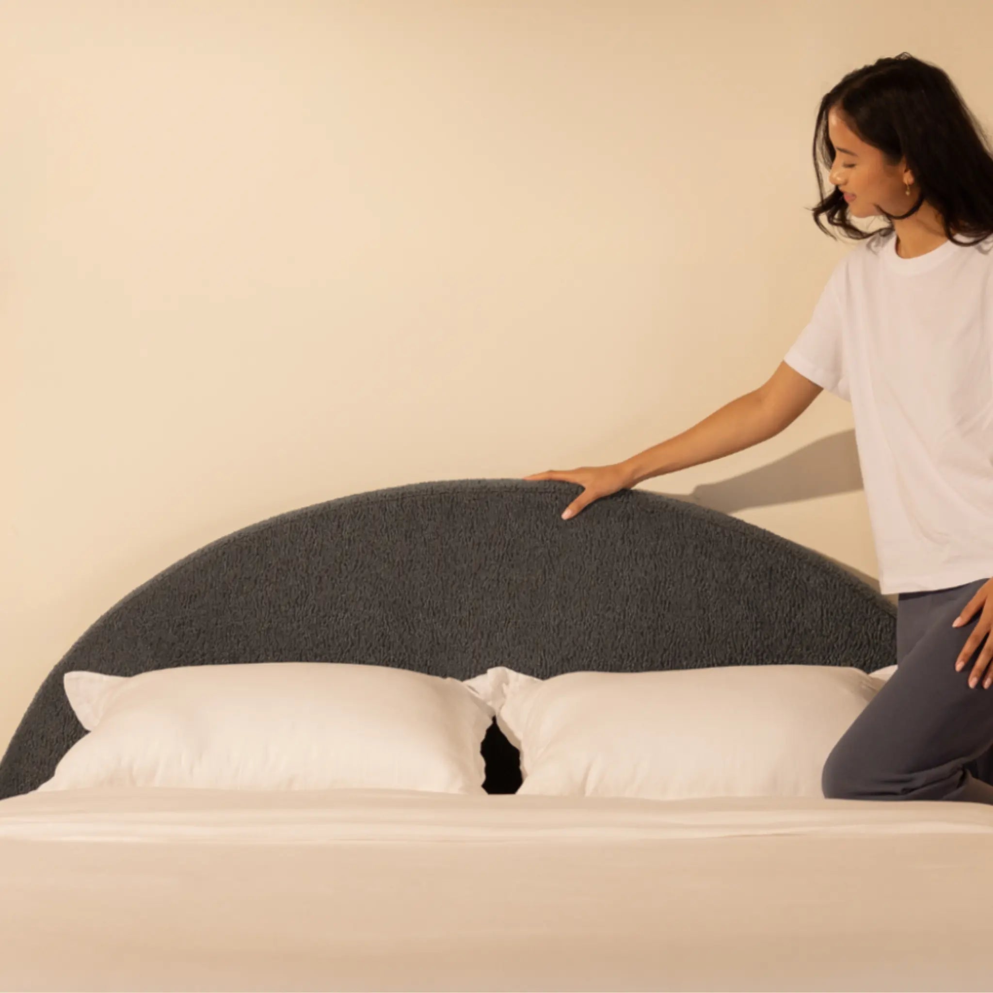 Person feeling a all cushioned headboard with a plain background